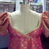 Bodice of an empire waisted dress with gold trim and puffed sleves. 