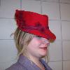 A red felt fedora was steamed and reshapen to mimic styles similar to those found in the 1880's and 1890's.  The hat has been adorned with a plum colored bias tape and burgundy flowers.