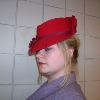 A red felt fedora was steamed and reshapen to mimic styles similar to those found in the 1880's and 1890's.  The hat has been adorned with a plum colored bias tape and burgundy flowers.